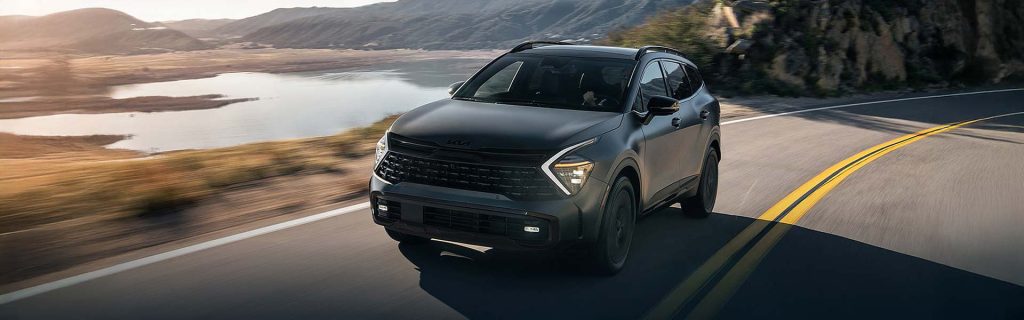 Kia Sportage Hybrid SUV driving along a scenic road by a lake.